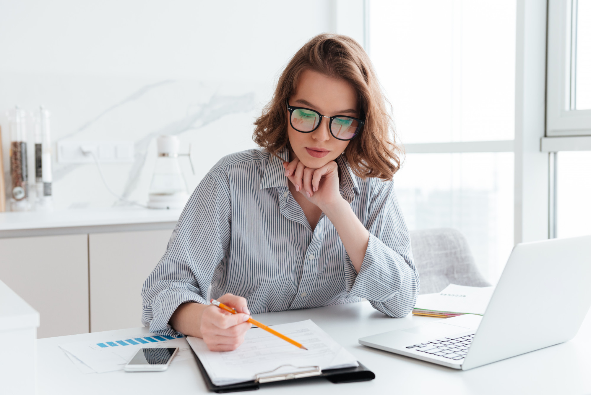 An image portraying the concept of professional accounting services in a modern business environment. The composition should include elements such as a clean office desk with accounting documents, a calculator, and a laptop, suggesting precision and professionalism. In the background, there could be a blurred view of a confident accountant or financial advisor interacting with a client, symbolizing trust and expertise. The overall scene represents the value and reliability of the company's services, catering to businesses in Kazakhstan.